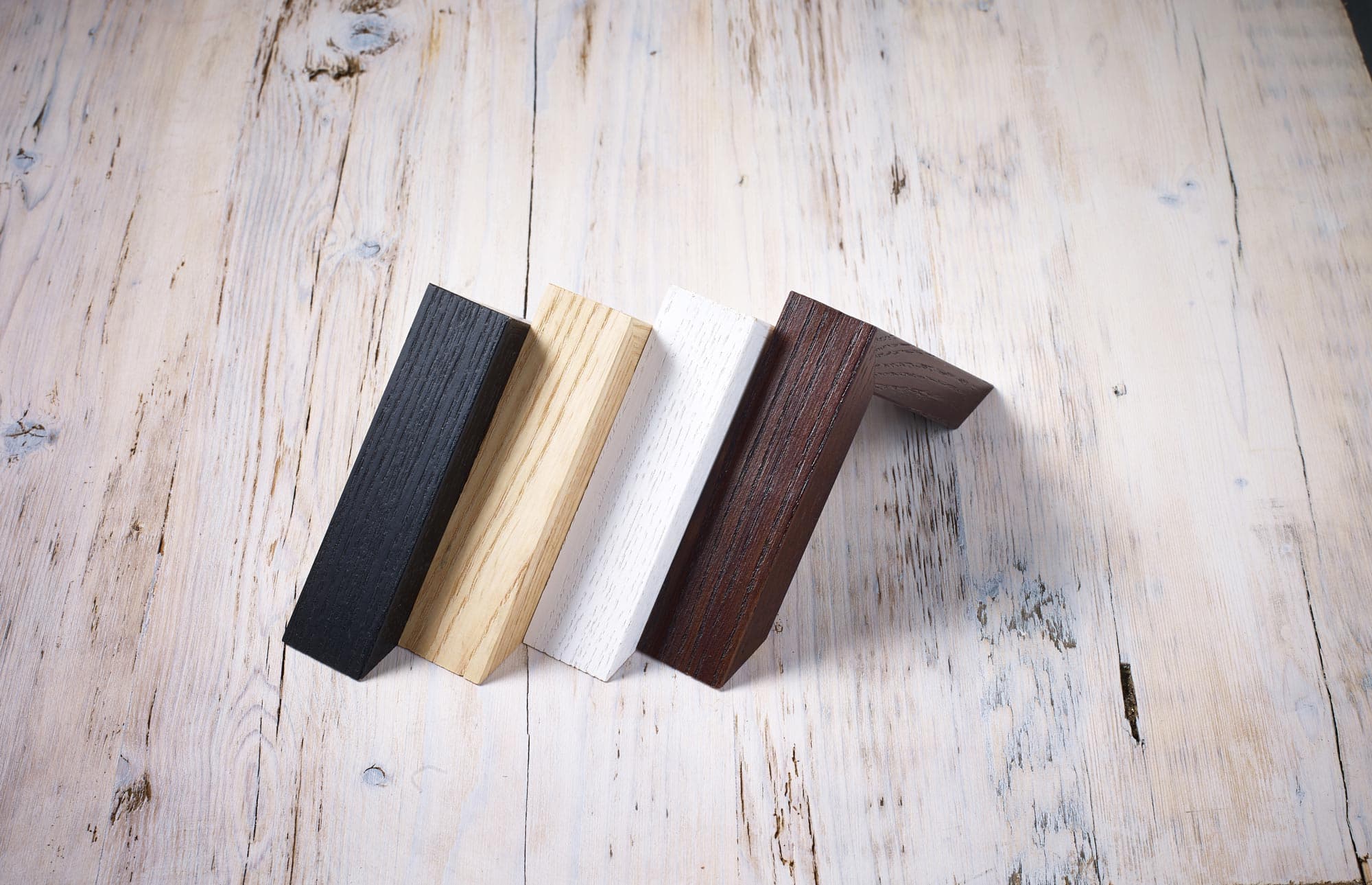Multiple wooden moulding corners stacked — different finishes side by side.